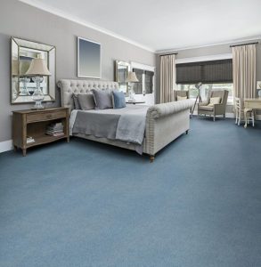 Large bedroom with sleigh bed, neutral furniture and deep blue/grey wool carpet.