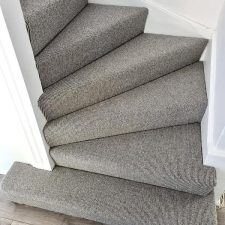 View of a flight of stairs fitted with grey wool loop carpet with a Ceneva Action Back.