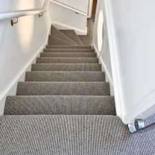 View down a flight of stairs fitted with grey wool loop carpet with a Ceneva Action Back.