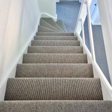 View down a flight of stairs fitted with grey wool loop carpet with a Ceneva Action Back.