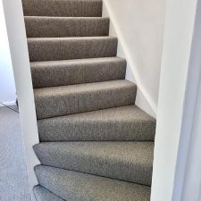 View of a flight of stairs fitted with grey wool loop carpet with a Ceneva Action Back.