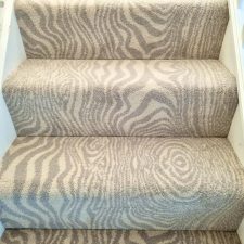 View of some stairs fitted with a patterned two-tone wood-effect beige woven axminster carpet.