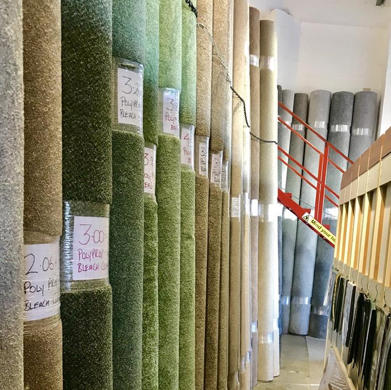 Rolls of remnant carpets standing up in the Sargeant Carpets showroom, in shades of green and beige.