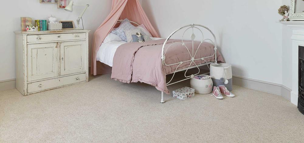 A child's bedroom with pink canopy over bed, distressed painted chest of drawers and berber ivory coloured carpet.