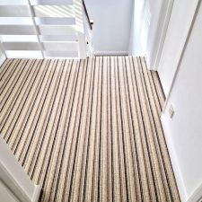 View of a landing fitted with a loop pile, wool/polyester brown and beige striped carpet.