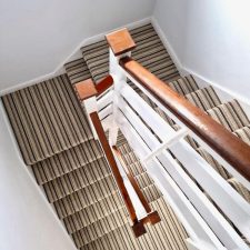 View down a flight of stairs fitted with a loop pile, wool/polyester brown and beige striped carpet.