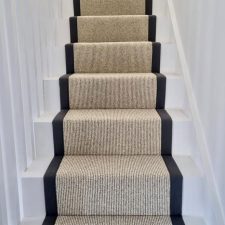 View up a flight of stairs fitted with undyed natural wool loop carpet, in a renovated house in West Wittering.