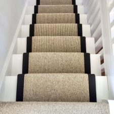 View down a flight of stairs fitted with undyed natural wool loop carpet, in a renovated house in West Wittering.