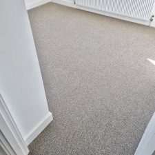 View into a bedroom fitted with neutral beige undyed natural wool loop carpet.