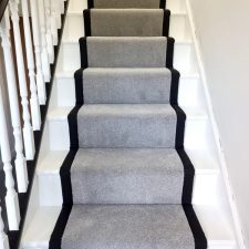 View up a flight of stairs covered with a grey twist pile fade resistant carpet and herringbone binding to the sides.