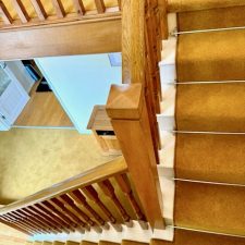 View of a flight of stairs fitted with a wool twist carpet runner with chrome stair rods.