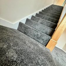 View up a flight of stairs fitted with a charcoal coloured nylon saxony carpet.