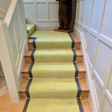 A lime green stair carpet with bracken shade of binding and brass stair rods.