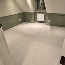 Beige carpet fitted in a loft room with sloped ceilings.
