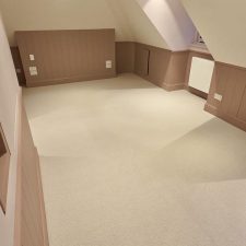 Beige carpet fitted in a loft room with sloped ceilings.